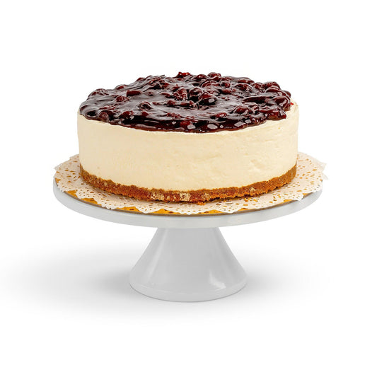 A whole Cheesecake with a smooth creamy filling, graham cracker crust, and topped with a glossy cherry compote, displayed on a white cake stand.