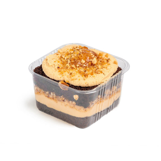 Individual Choco-Crunchy Hazelnut Cake Cup featuring layers of chocolate cake, hazelnut frosting, crunchy chocolate bits, and caramel drizzle.