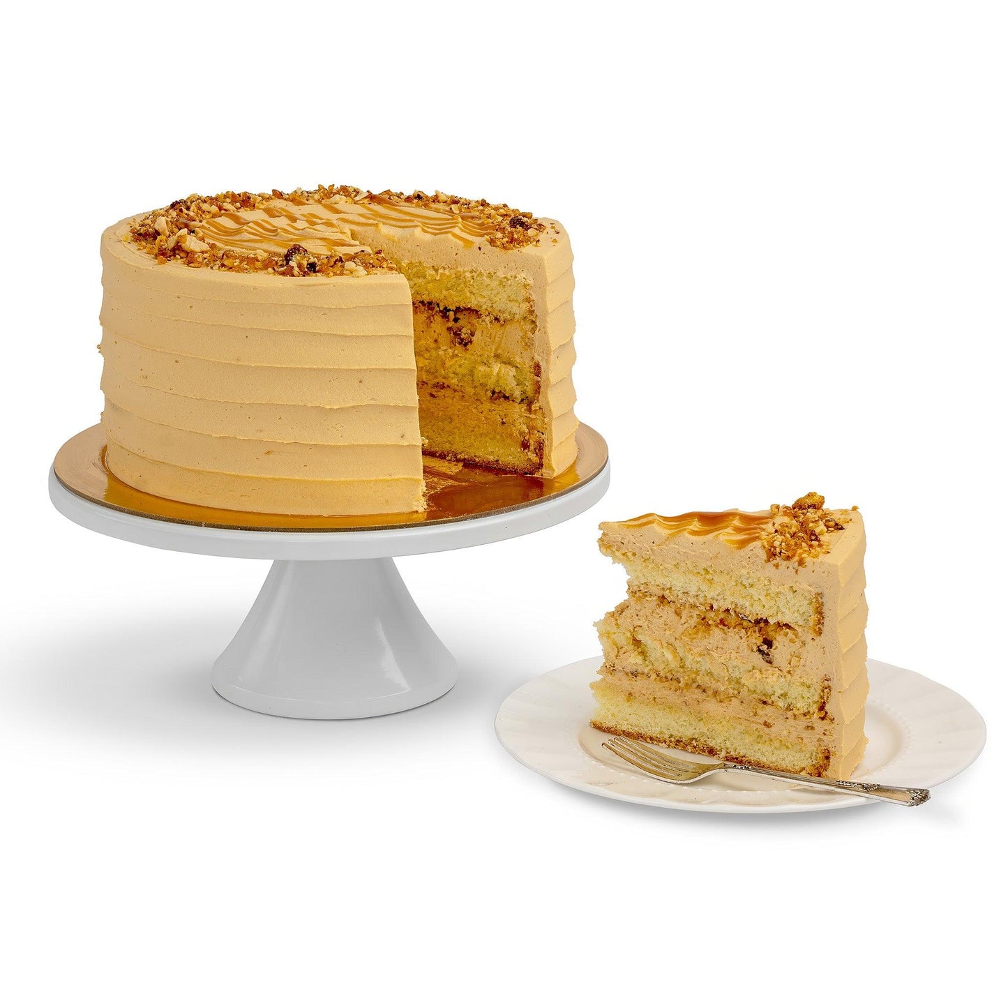 A Vanilla-Crunchy Hazelnut Cake with a slice removed, showcasing fluffy vanilla layers, hazelnut frosting, and a caramel nut topping, served on a plate.